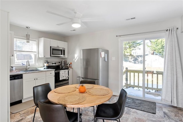 kitchen featuring appliances with stainless steel finishes, pendant lighting, white cabinetry, and sink