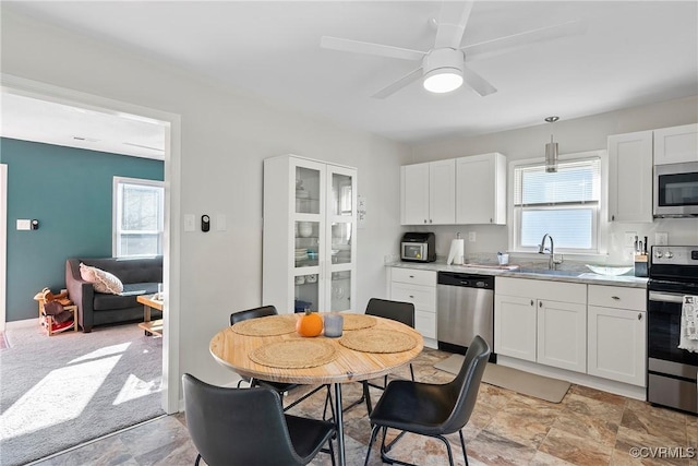 kitchen featuring pendant lighting, white cabinetry, stainless steel appliances, sink, and ceiling fan