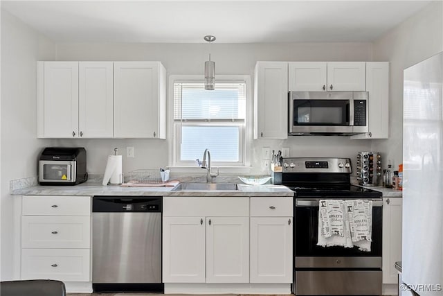 kitchen with decorative light fixtures, white cabinets, sink, and stainless steel appliances