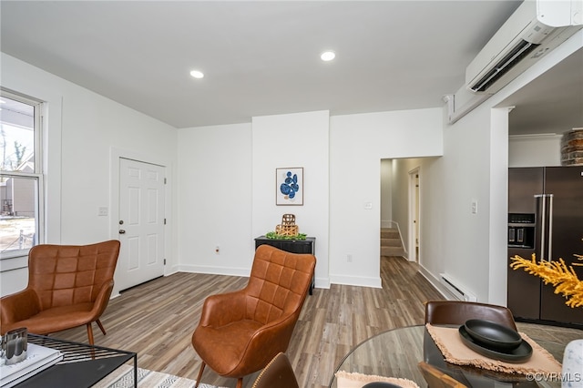 sitting room with a baseboard heating unit, hardwood / wood-style flooring, and a wall unit AC