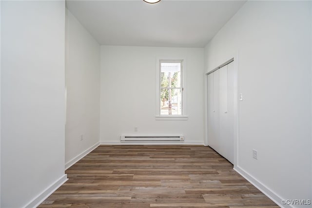 unfurnished room featuring a baseboard heating unit and dark wood-type flooring