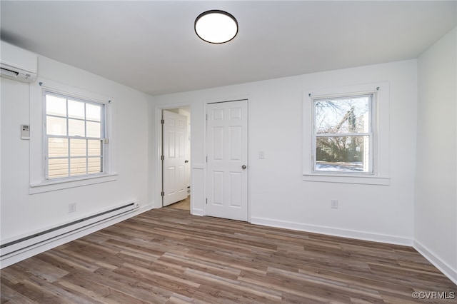 spare room with baseboard heating, dark hardwood / wood-style flooring, and a wall mounted AC