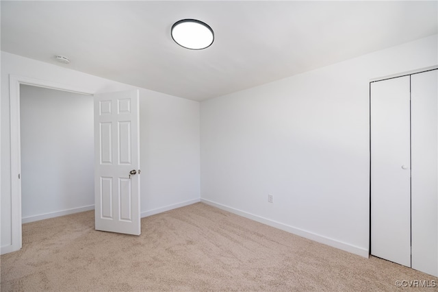 unfurnished bedroom featuring light colored carpet and a closet