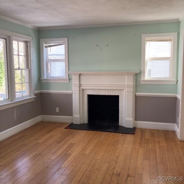 unfurnished living room featuring a fireplace, crown molding, and light hardwood / wood-style flooring