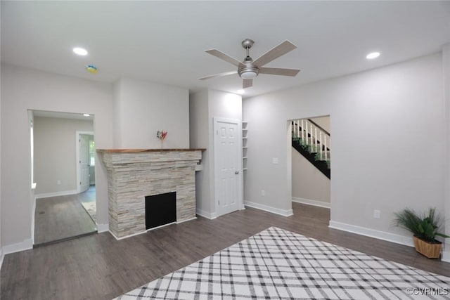 living room featuring ceiling fan, dark wood-type flooring, and a fireplace