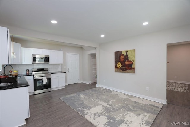 kitchen with appliances with stainless steel finishes, dark countertops, white cabinetry, and decorative backsplash