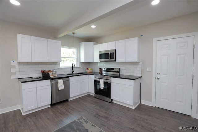 kitchen with stainless steel appliances, dark countertops, white cabinetry, and a sink