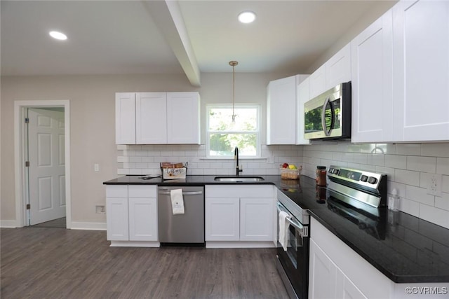 kitchen featuring stainless steel appliances, pendant lighting, white cabinets, and sink