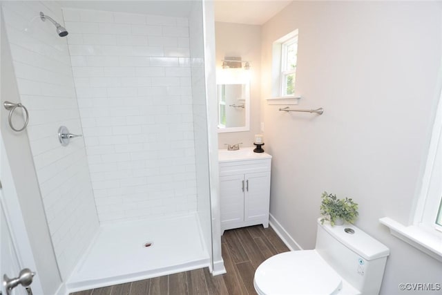 bathroom with toilet, a tile shower, and vanity