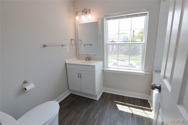 bathroom featuring hardwood / wood-style flooring, a wealth of natural light, toilet, and vanity