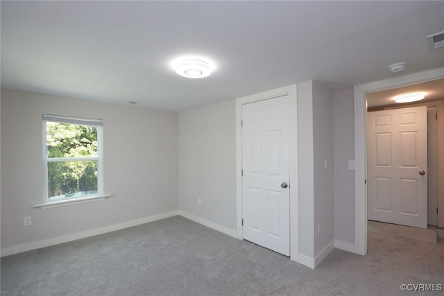 unfurnished room with light colored carpet, visible vents, and baseboards