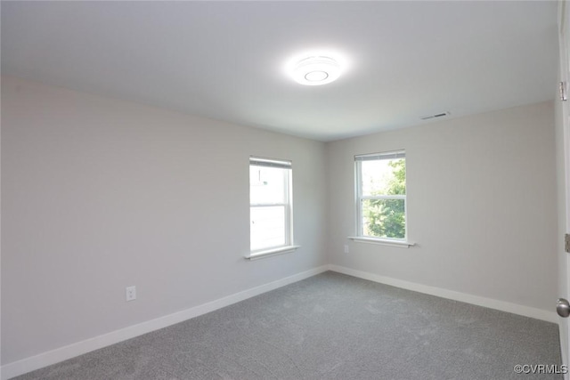 carpeted spare room with visible vents and baseboards