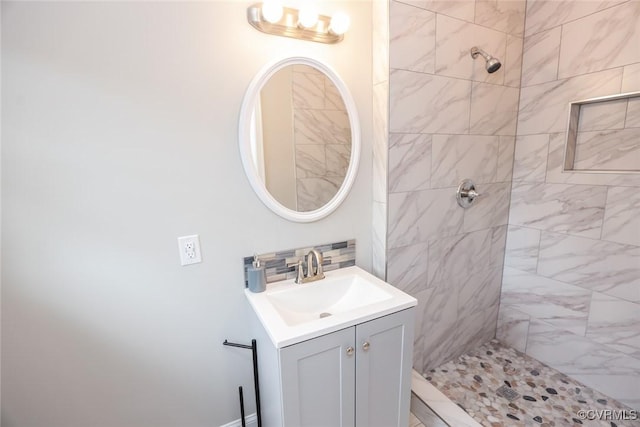 bathroom featuring decorative backsplash, tiled shower, and vanity