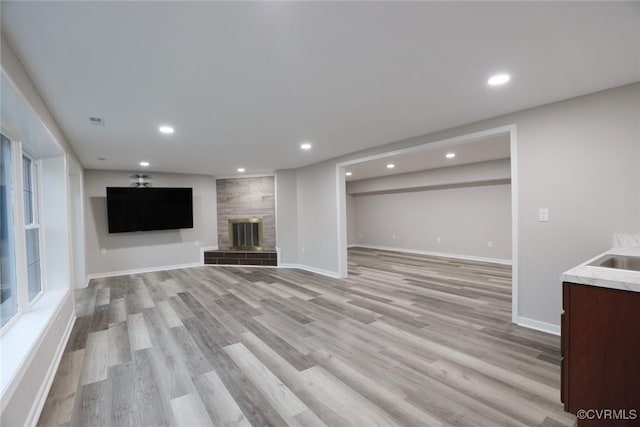 unfurnished living room featuring sink, light wood-type flooring, and a tile fireplace