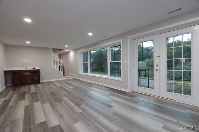 unfurnished living room with sink, french doors, and light wood-type flooring