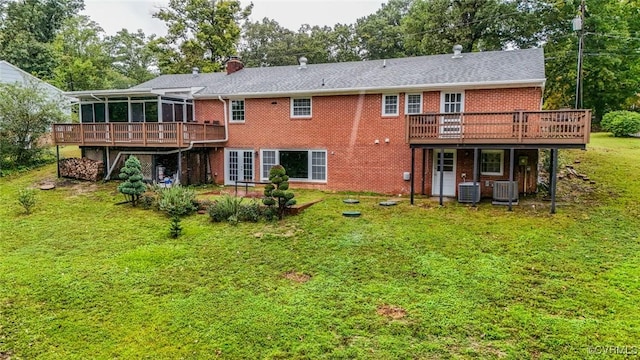 rear view of house with a wooden deck, cooling unit, a lawn, and a sunroom