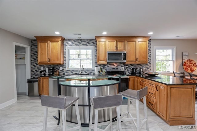 kitchen featuring stainless steel appliances, tasteful backsplash, dark stone countertops, sink, and kitchen peninsula