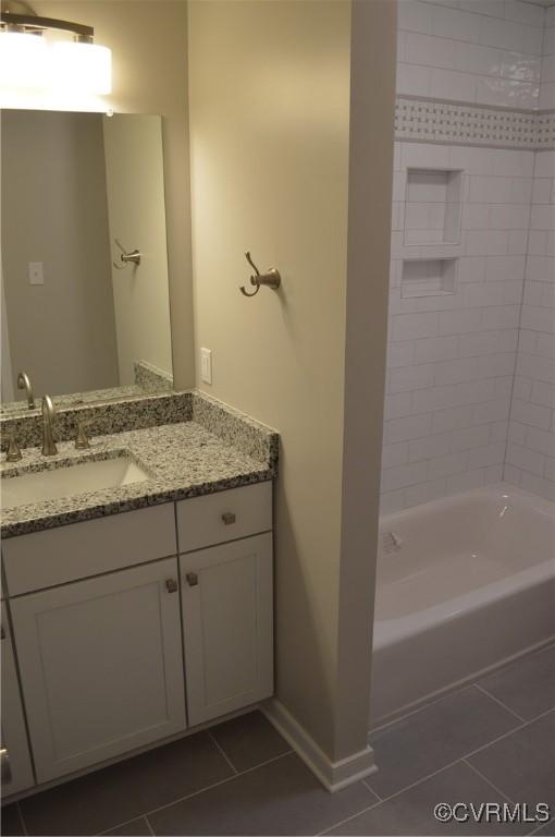 bathroom with tiled shower / bath combo, vanity, and tile patterned flooring