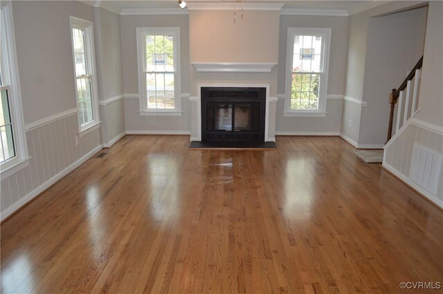 unfurnished living room with a wealth of natural light, light hardwood / wood-style flooring, and ornamental molding