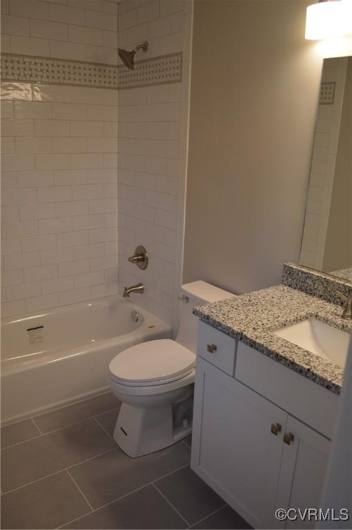 full bathroom with toilet, tiled shower / bath, tile patterned floors, and vanity