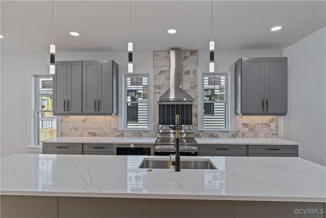 kitchen featuring stainless steel range with electric stovetop, light stone countertops, gray cabinetry, and wall chimney range hood