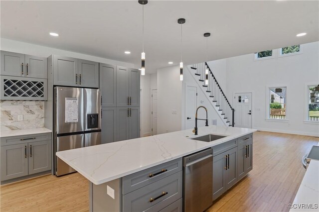 kitchen featuring sink, gray cabinetry, stainless steel appliances, and an island with sink