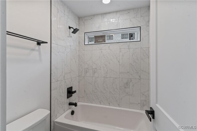 bathroom with toilet and tiled shower / bath