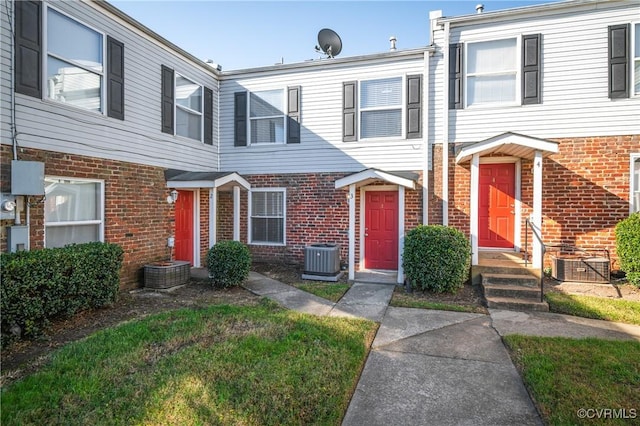 view of property featuring central AC unit and a front lawn