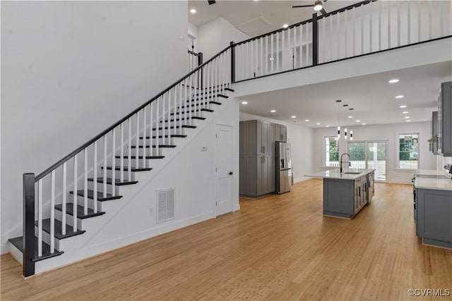 staircase with hardwood / wood-style flooring, sink, and ceiling fan