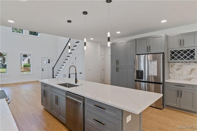 kitchen with appliances with stainless steel finishes, gray cabinetry, backsplash, pendant lighting, and sink