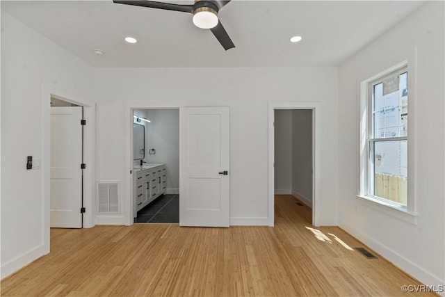 unfurnished bedroom with ceiling fan, connected bathroom, and light wood-type flooring