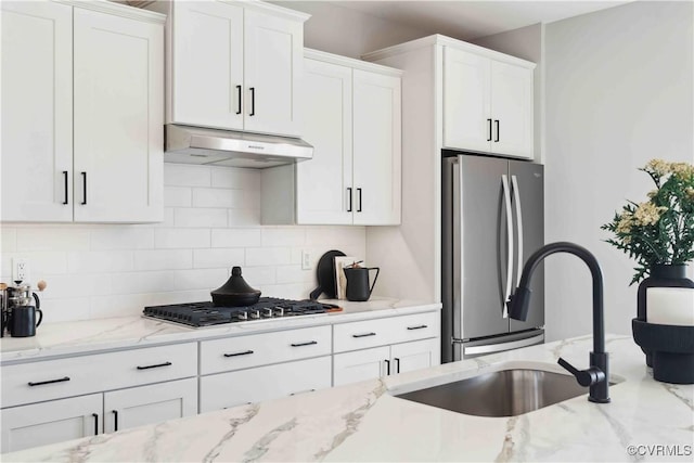 kitchen with under cabinet range hood, white cabinetry, appliances with stainless steel finishes, and decorative backsplash