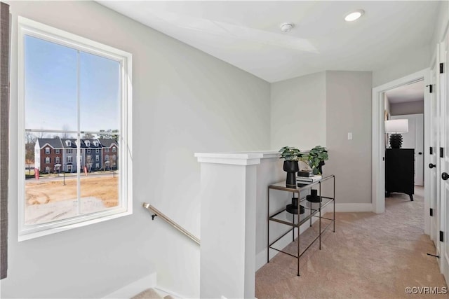 hallway with carpet, baseboards, and an upstairs landing