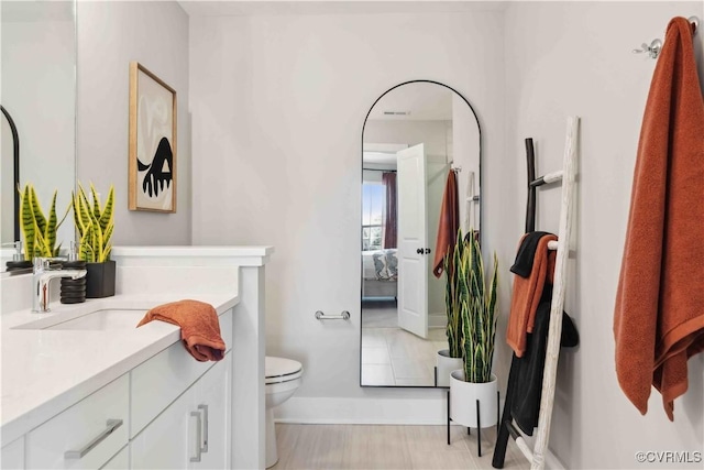 ensuite bathroom featuring vanity, ensuite bath, and toilet