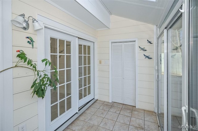 doorway to outside featuring light tile patterned flooring and wooden walls