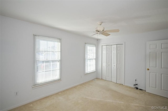 unfurnished bedroom with ceiling fan, light carpet, and a closet