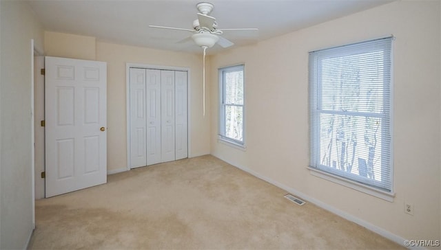 unfurnished bedroom featuring ceiling fan, light colored carpet, and a closet