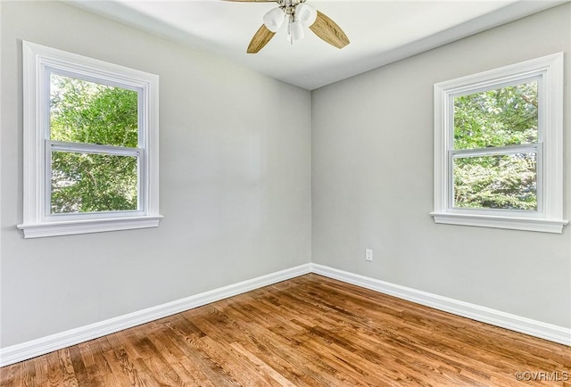 empty room featuring ceiling fan, a healthy amount of sunlight, and hardwood / wood-style floors