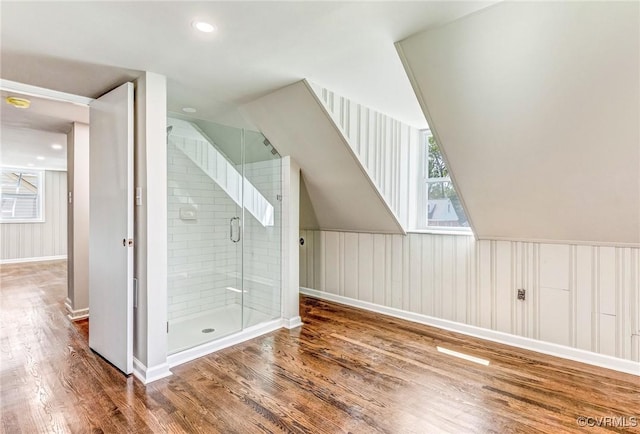 bathroom with wood-type flooring, a shower with door, and lofted ceiling