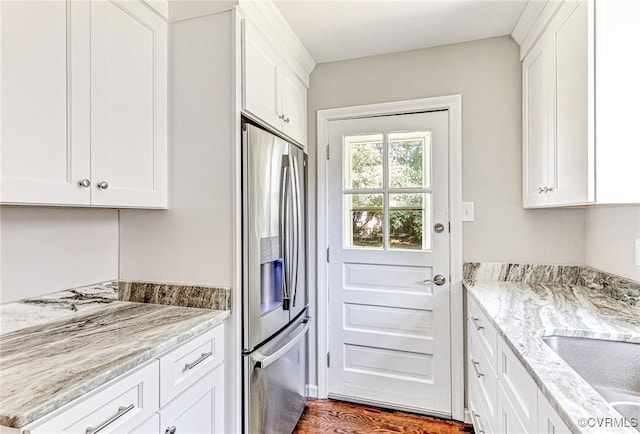 kitchen with stainless steel refrigerator with ice dispenser, light stone counters, and white cabinets