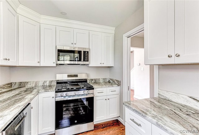 kitchen featuring white cabinets, appliances with stainless steel finishes, light stone counters, and light hardwood / wood-style floors