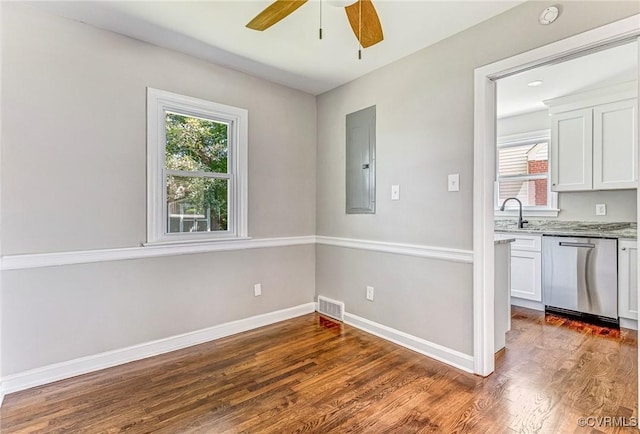 kitchen with dark hardwood / wood-style floors, electric panel, stainless steel dishwasher, light stone countertops, and white cabinets