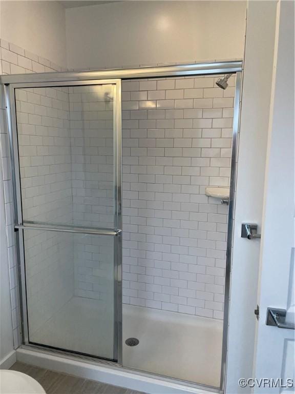 bathroom featuring a shower with shower door, wood-type flooring, and toilet