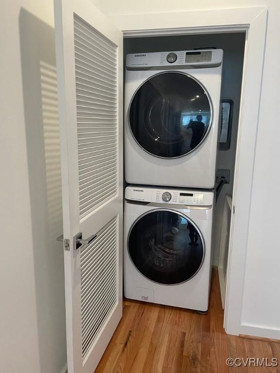 washroom with hardwood / wood-style floors and stacked washer and dryer