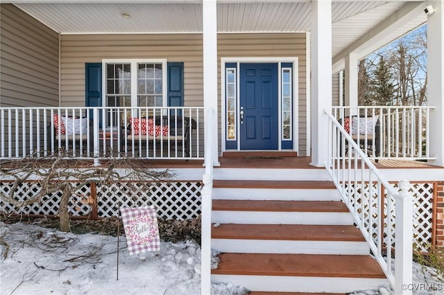 snow covered property entrance with covered porch