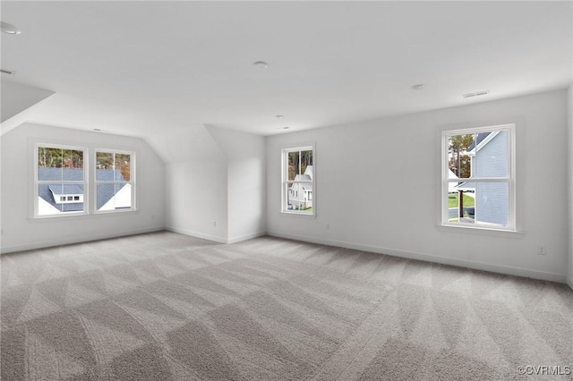 bonus room with a wealth of natural light, lofted ceiling, and light carpet