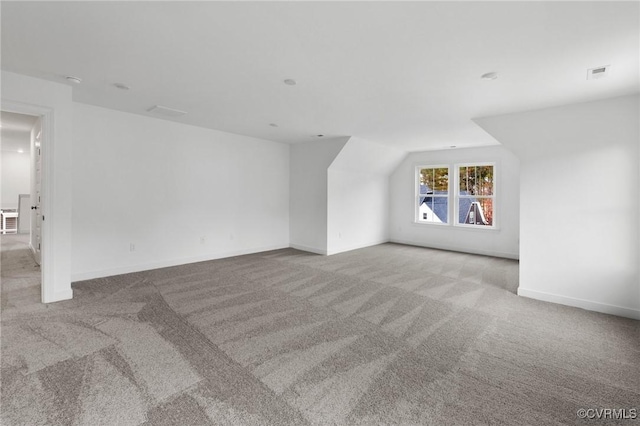 bonus room with lofted ceiling and light colored carpet