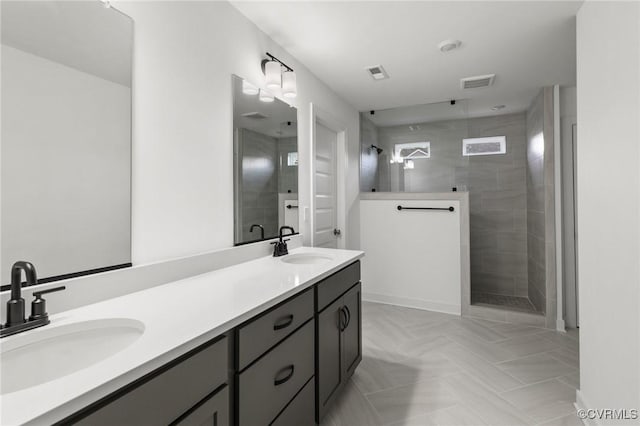 bathroom with a tile shower and vanity