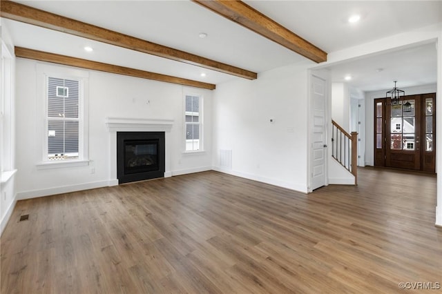 unfurnished living room featuring hardwood / wood-style flooring and beamed ceiling