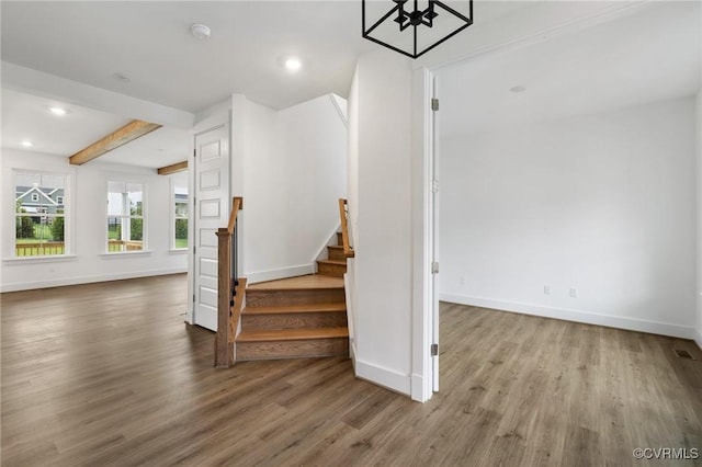 staircase featuring beamed ceiling and hardwood / wood-style floors